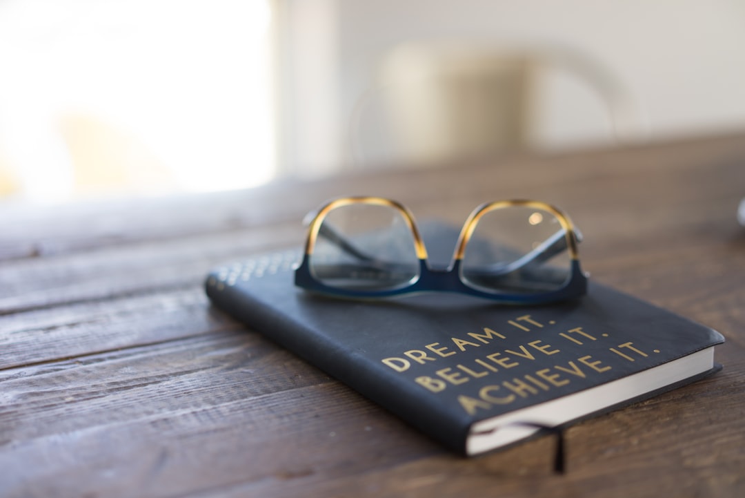 Photo by carolyn christine black and brown eyeglasses on book on brown wooden table