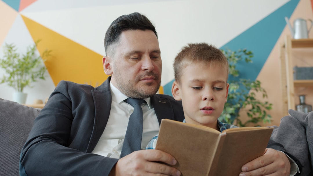 Photo by Vitaly Gariev Father and son reading a book together